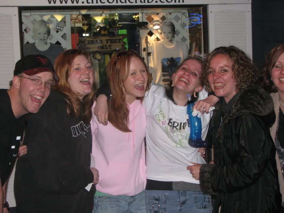 Group of friends laughing outside a lit storefront at night