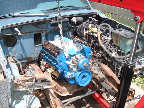 1990 Ford Ranger - An engine is being installed into a truck's engine bay using an engine hoist.