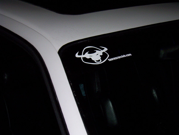 Car interior showing a sticker on the windshield with a bull logo and 'tauruscarclub.com'