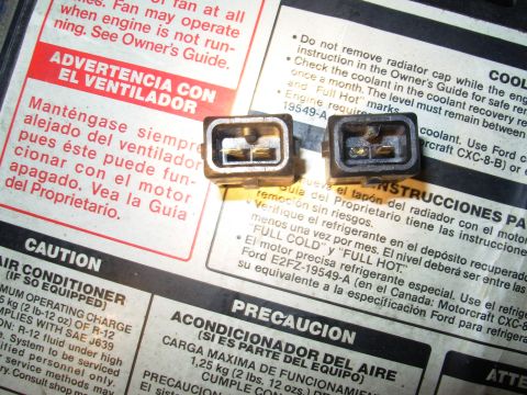 1995 Ford Taurus - Close-up of two electrical connectors resting on a document with various warnings and instructions.