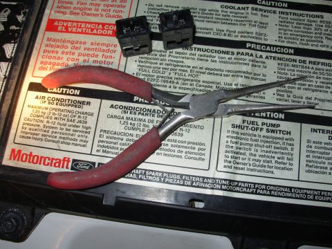 1995 Ford Taurus - Tools are placed on a car battery label that contains various warnings and instructions.