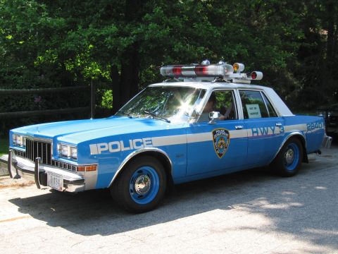 1991 Ford Crown Victoria - This blue and white police car displays "POLICE" and "HWY 3" markings, with an "OUT OF SERVICE" sign visible in the rear window.