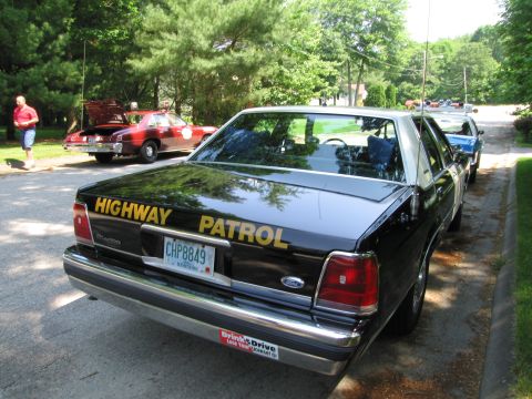 1991 Ford Crown Victoria - A black 1991 Ford Crown Victoria, marked as Highway Patrol, is parked in a line with other vehicles.