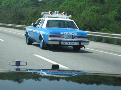 1991 Ford Crown Victoria - A police car with an 'OUT OF SERVICE' plate is seen driving on the highway.