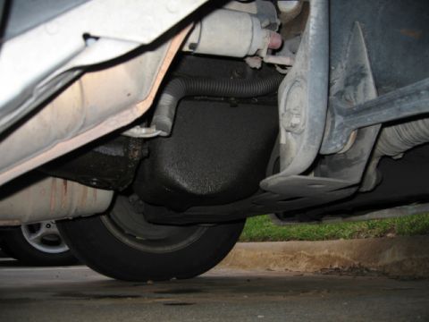 1995 Mercury Cougar - Close-up view of the undercarriage of a vehicle, revealing mechanical components and a tire.