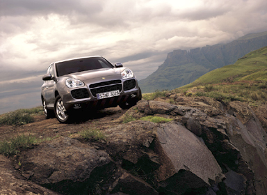 1993 Ford Taurus - Porsche Cayenne SUV navigates a , mountainous terrain under a cloudy sky.
