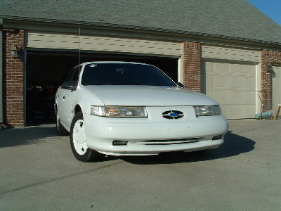1993 Ford Taurus - Front view of a white 1993 Ford Taurus parked in front of a residential garage.