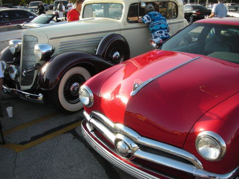 1998 Ford Crown Victoria - Two classic cars parked side-by-side at an outdoor event.