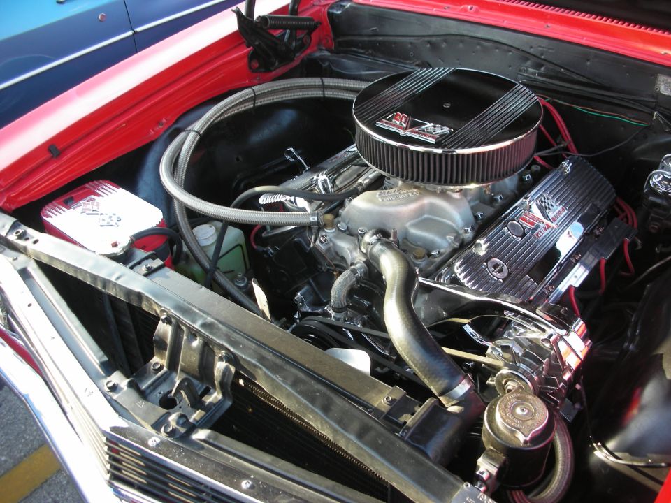 Engine bay with chrome valve covers and air cleaner. Red fender and blue stripe visible
