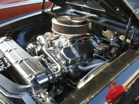 1998 Ford Crown Victoria - The engine bay of a car is shown, with a second vehicle partially visible in the background.