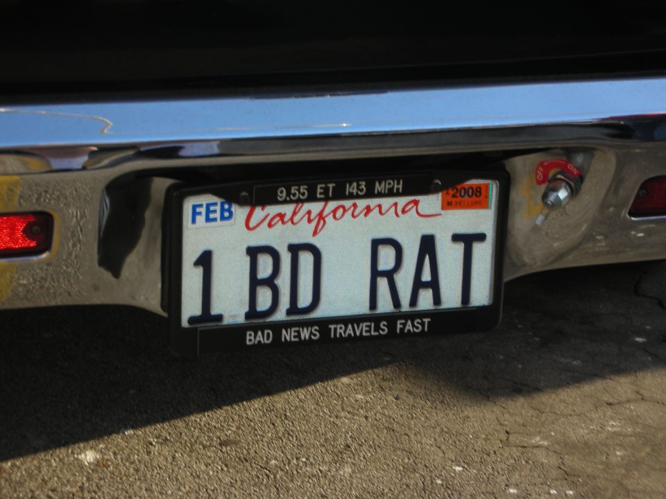 California license plate '1 BD RAT' on a vehicle bumper. Plate has 'BAD NEWS TRAVELS FAST' below