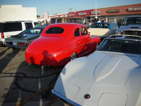 1998 Ford Crown Victoria - A red coupe is parked in a lot with other vehicles and businesses in the background.