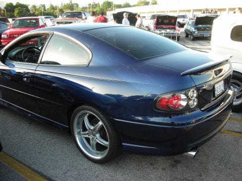 1998 Ford Crown Victoria - A dark blue coupe is parked in a lot with other vehicles and people visible in the background.