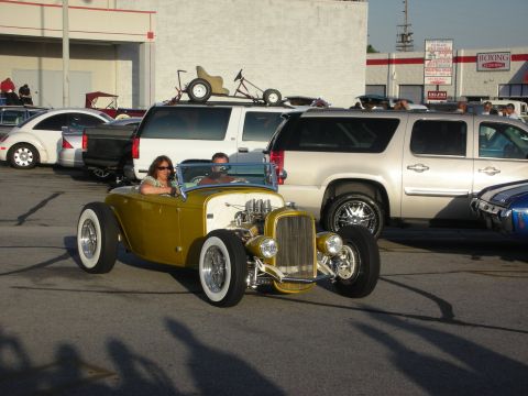 1998 Ford Crown Victoria - A gold hot rod roadster is parked in front of several SUVs and other vehicles.