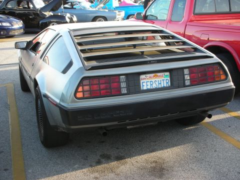 1998 Ford Crown Victoria - A DeLorean DMC-12 is seen from the rear, parked in a lot with other vehicles.