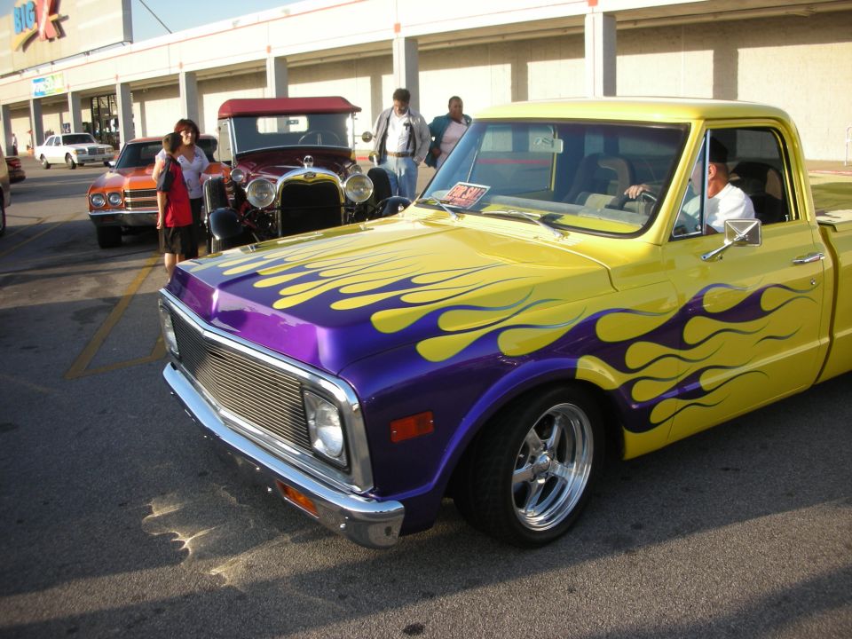 Yellow pickup truck with purple flames, chrome grille, and custom wheels