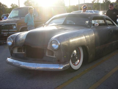1998 Ford Crown Victoria - A custom hot rod with a bare metal body and wide whitewall tires sits in a parking lot.