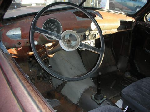 1998 Ford Crown Victoria - The interior of this classic vehicle shows significant wear and tear, with a prominent steering wheel and exposed metalwork.