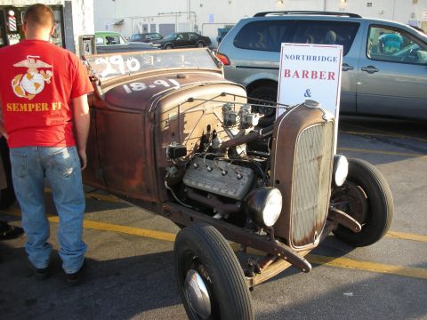 1998 Ford Crown Victoria - A weathered hot rod sits in a parking lot, its engine exposed and ready for work.