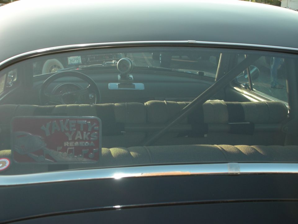 Interior view through rear window of a car, showing roll cage, seats, and a 'Yakety Yaks' sticker