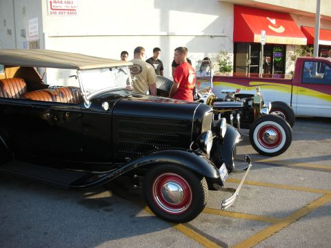 1998 Ford Crown Victoria - Two custom vehicles, a hot rod and a pickup truck, are parked side-by-side in a lot.