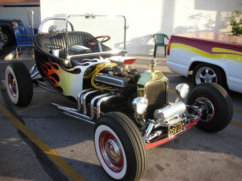 1998 Ford Crown Victoria - This custom hot rod features flame decals on its body and a prominent V8 engine. A second vehicle is partially visible in the background.