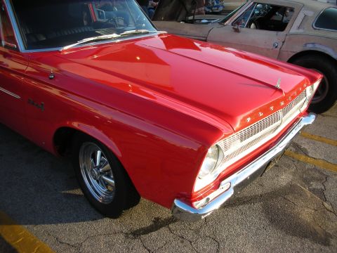 1998 Ford Crown Victoria - Front view of a red 1965 Plymouth Barracuda, with another vehicle in the background.