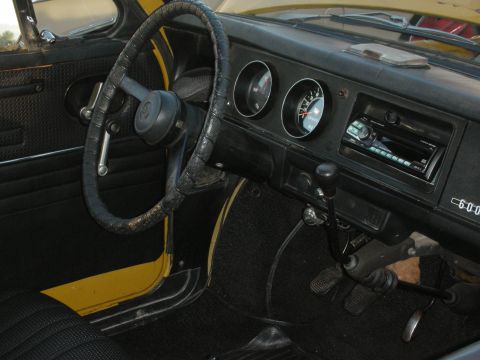 1998 Ford Crown Victoria - The interior of a vintage car features a worn steering wheel, dual gauges, and an aftermarket radio installed in the dash.