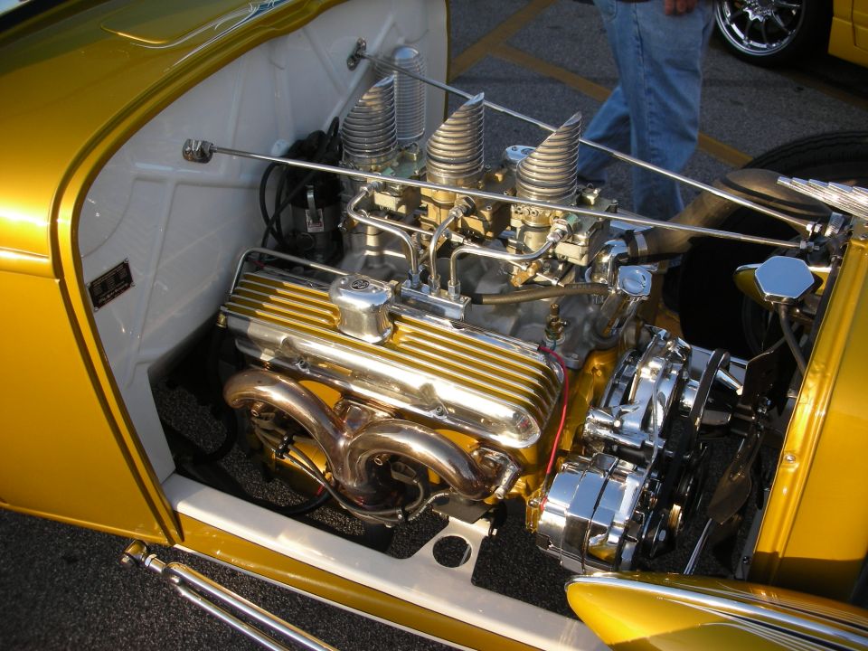 Custom V8 engine with gold finned valve covers and triple carburetors, chrome headers