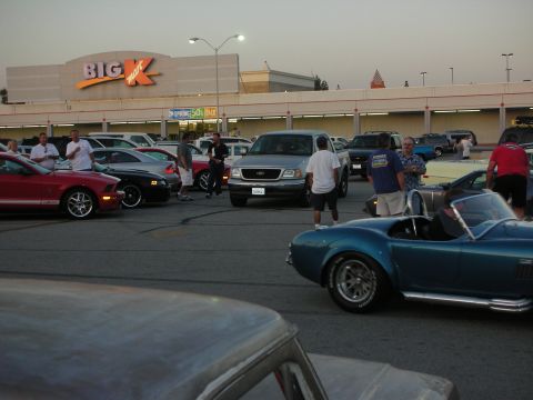 1998 Ford Crown Victoria - A silver Ford F-150 pickup truck is parked in a lot, with several other vehicles and people around.