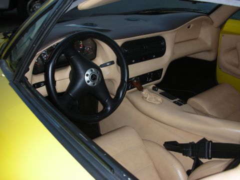 1998 Ford Crown Victoria - The interior of a yellow sports car features tan leather seats, a black steering wheel, and a wood-accented gear shifter.