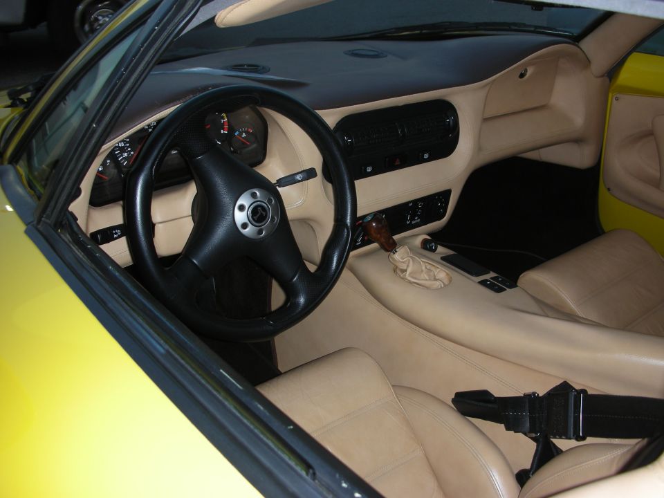 Interior of a yellow sports car with tan leather seats and a black steering wheel