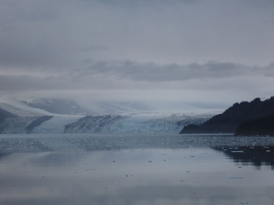 Glacier calving into the sea under a cloudy sky