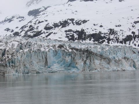 1973 Ford Ranchero - A large glacier with textured blue ice meets the water under a snow-capped mountain range.
