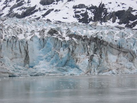 1973 Ford Ranchero - A vast glacier face, showing layers of ice and rock, meets the ocean under a snowy mountain range.