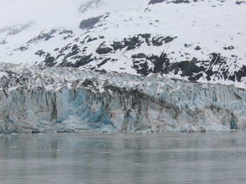 1973 Ford Ranchero - A massive glacier face shows layers of blue ice and dark debris, with snow-capped mountains looming in the background.