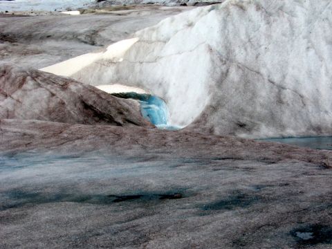 1973 Ford Ranchero - A close-up view of a glacier's surface, showing textured ice and a small opening with flowing meltwater.