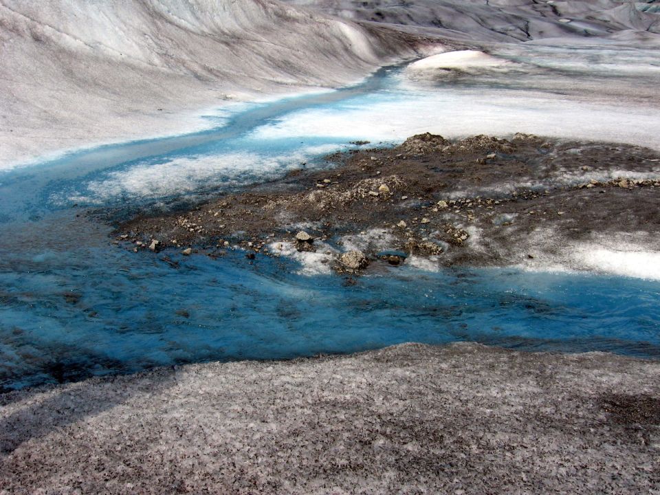 Glacial meltwater stream with blue water flowing over ice and rocks