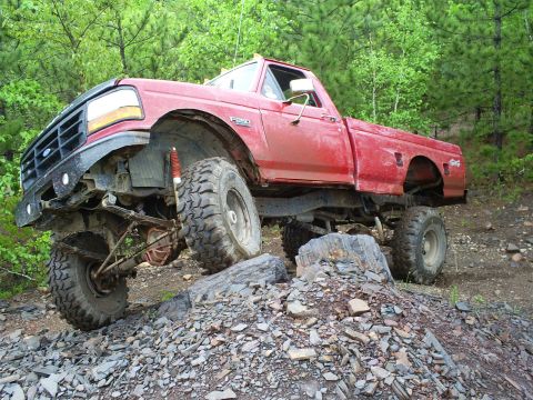 1994 Ford F-250 - This modified pickup truck navigates a rocky trail with its suspension clearly visible.