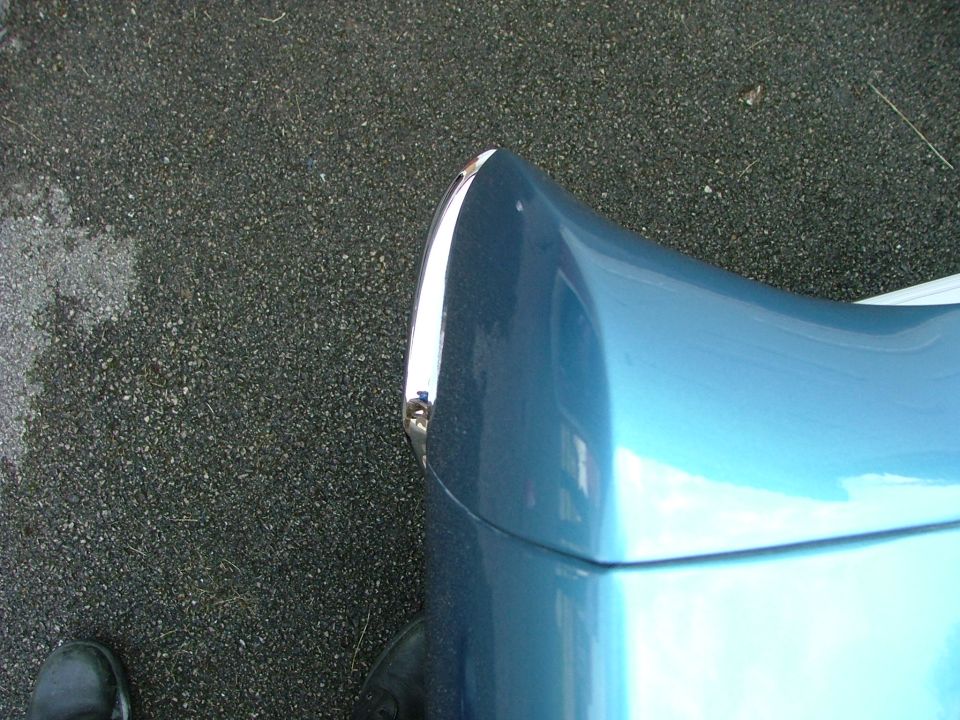 Close-up of a blue car's fender with a chrome trim piece