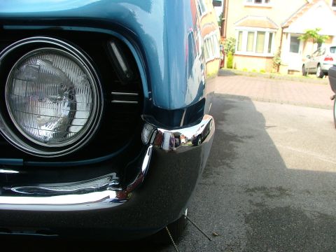 1970 Ford Ranchero - Close-up of a blue 1968 Ford Ranchero's front corner, showing the headlight and chrome bumper.
