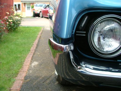 1970 Ford Ranchero - Close-up of the front corner of a blue 1970 Ford Ranchero, showing the headlight and chrome bumper.
