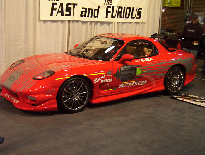 Red Fast and the Furious Mazda RX-7 movie car on indoor display under a movie banner