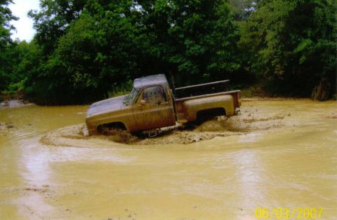 1976 Chevrolet Blazer - Pickup truck navigating through a muddy water obstacle.