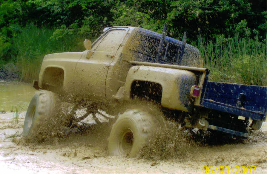 Muddy 1976 Chevrolet Blazer driving through water and mud