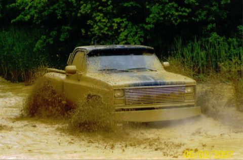 1976 Chevrolet Blazer - Pickup truck navigates a muddy terrain, kicking up spray.