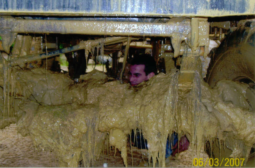 Undercarriage of a mud-covered vehicle with a person visible