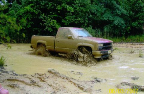 1976 Chevrolet Blazer - This tan pickup truck is deeply stuck in the mud, with water and mud splashing around its wheels.
