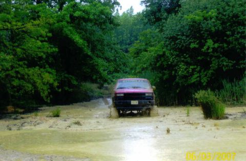 1976 Chevrolet Blazer - This pink SUV navigates a muddy trail, kicking up water as it goes.