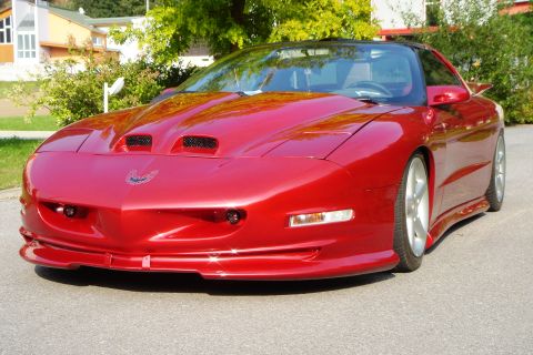 1993 Pontiac Firebird - Front 3/4 view of a red 1993 Pontiac Firebird with distinctive hood scoops.